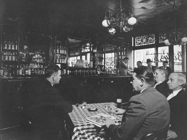 56th Street and First Avenue, New York City, an old-fashioned scene from Billy's Bar, with people sitting at a table near the bar. 
