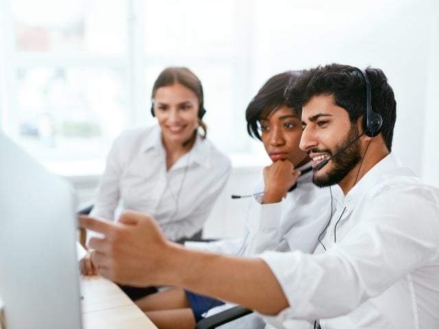 Three contact center agents looking at a computer screen.