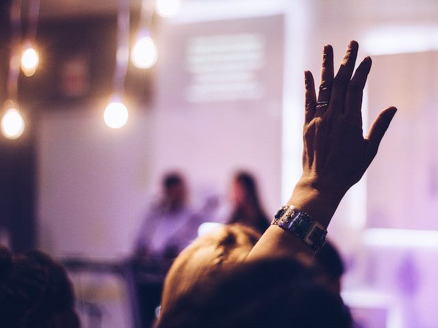 woman raising her hand in an audience