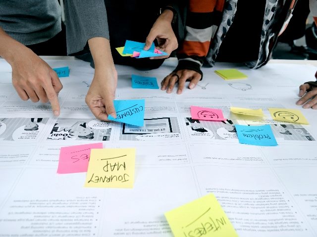 Shot of colleagues doing customer journey mapping with sticky notes and paper.
