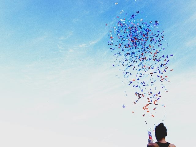 Confetti shooting out, ignited by a person in the bottom right corner.