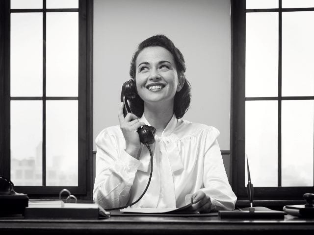 Smiling receptionist at work, black and white photo. 