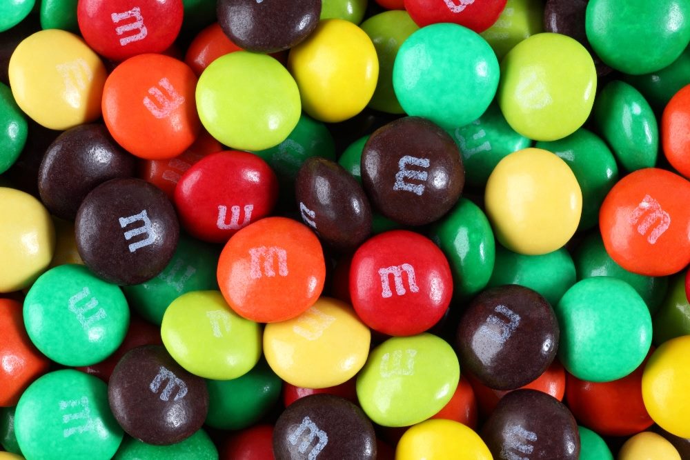 A closeup of M&M's candies scattered in various colors, such as red, green, yellow orange and brown in piece about marketing leadership.