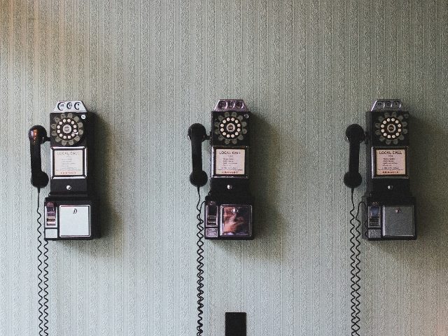 Three old-fashioned phones on a wall.
