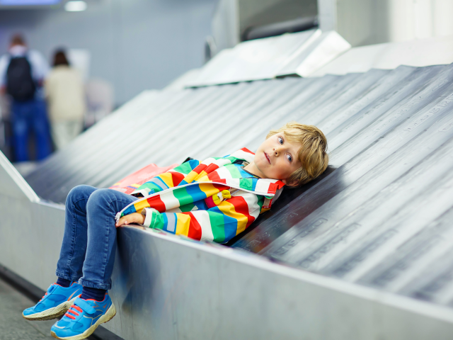 A tired child laying on the baggage claim pick up belt at the airport - Poor Customer Service 