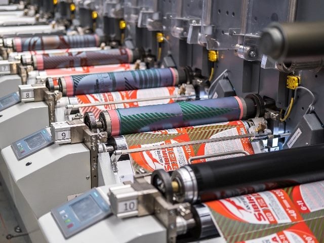 Rows of large offset printing press. moving polymer label conveyor printing magazines.
