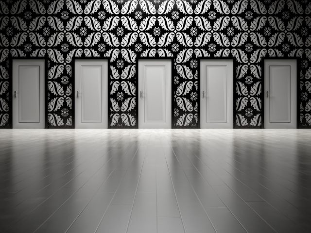 Multiple doors lined up on wall with decorative black and white flourishes. 