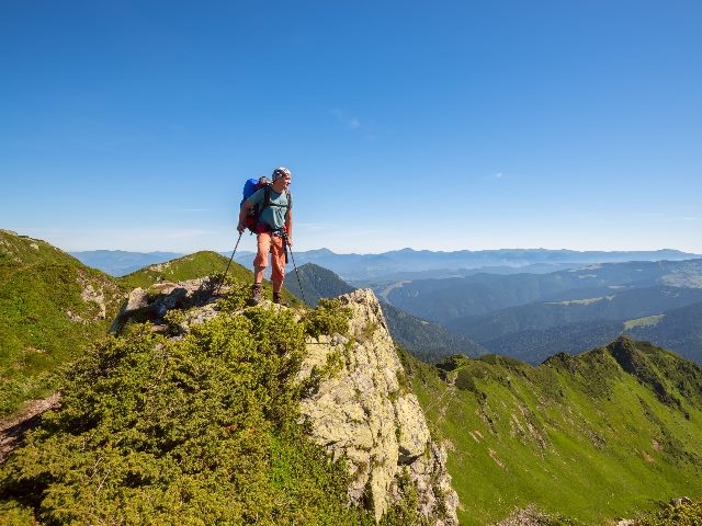 Backpacker standing on a rock over the cliff