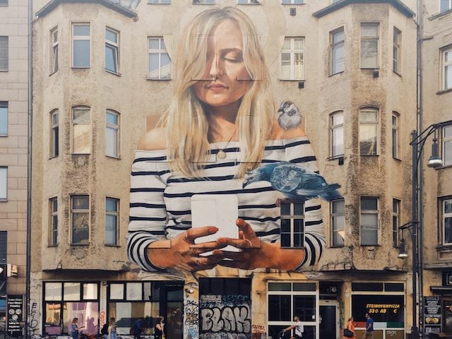 graffiti on a building of woman taking a selfie 