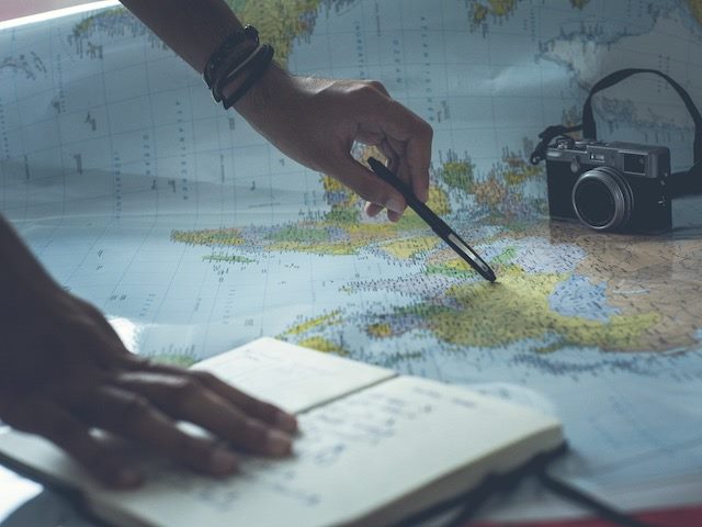 person mapping  out a route with camera and book in  frame