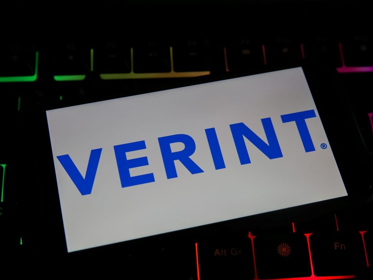 A white card displaying the blue Verint logo placed on top of a backlit computer keyboard with colorful RGB lighting.