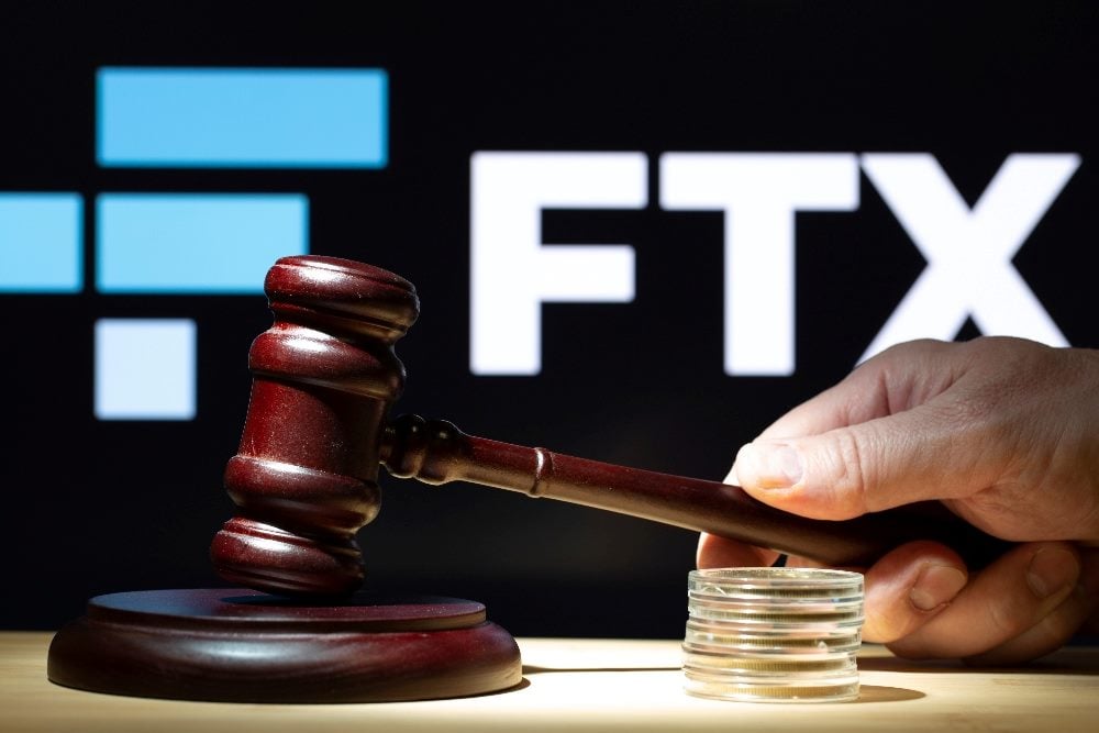 A judge's gavel is in the foreground with the FTX logo in white and blue in the background in piece about Bankman-Fried trial.