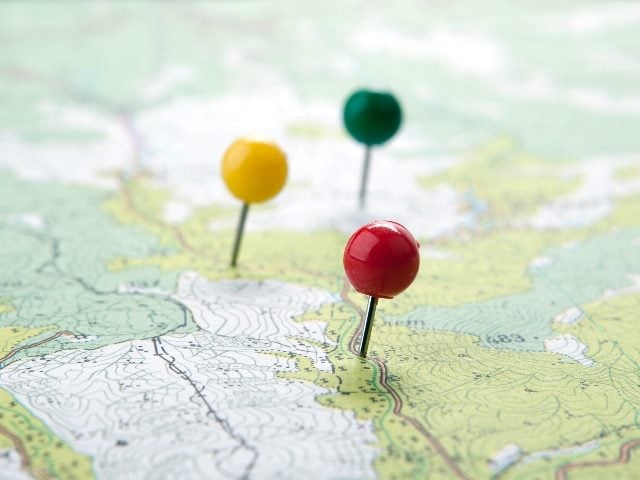  Topographic map with colored needles pushpins close up.