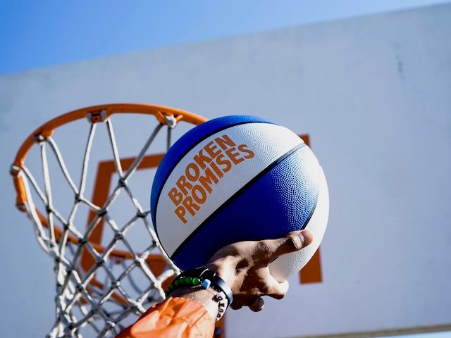 man about to make a slam dunk with a basketball that reads "broken promises"