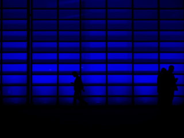 people walking in front of a blue wall