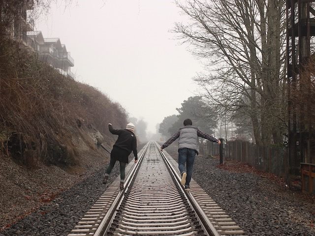 two people balancing on train tracks