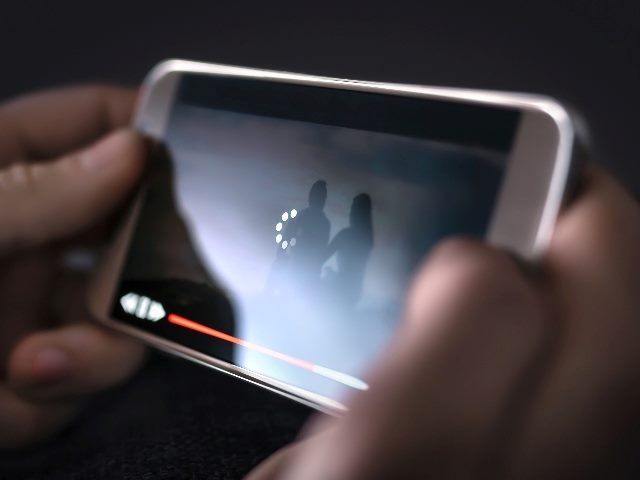 Someone, showing just their hands, watching a video on a mobile phone. 