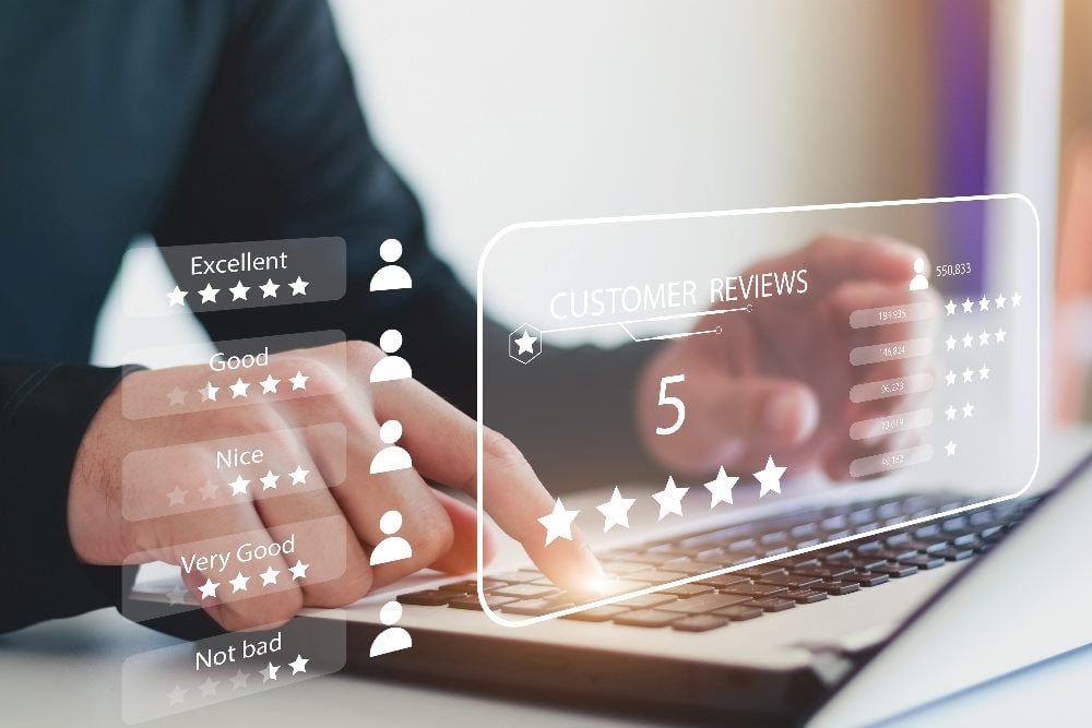 A customer wearing a dark long-sleeved shirt sits in front of an open laptop and fills out a customer feedback survey with customer icons and star icons visible in piece about marketing and CX goals.