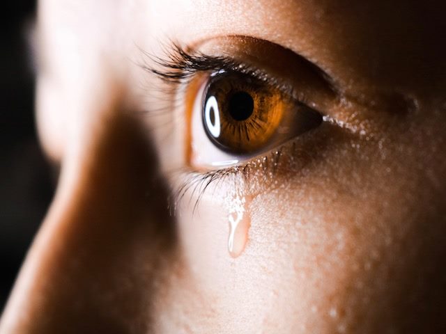 close up of a woman's eye with one tear running down her cheek