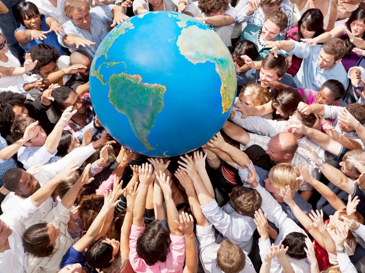 Claude responded: A diverse crowd of people reaching up together to hold a large globe aloft, their hands supporting it from below and around the sides, shot from above.A diverse crowd of people reaching up together to hold a large globe aloft, their hands supporting it from below and around the sides, shot from above.