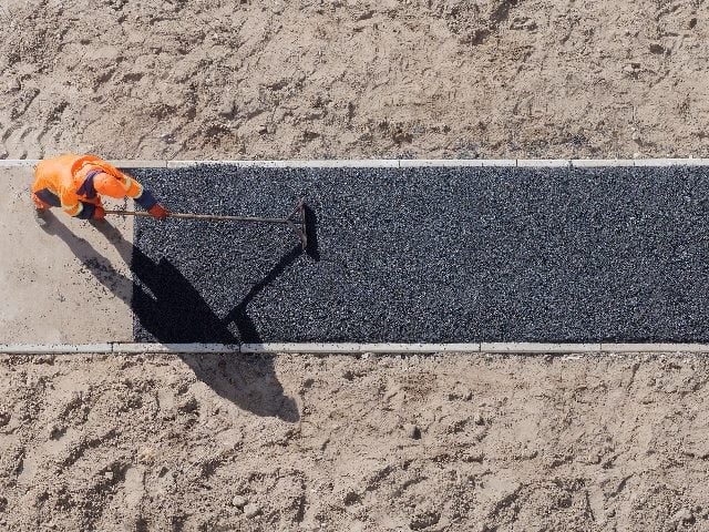 Aerial view of worker laying new asphalt on a pathway. 