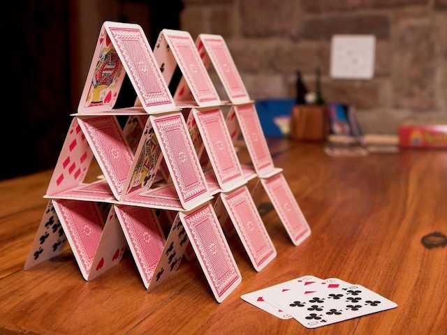 house of cards on a wood table, connoting instability