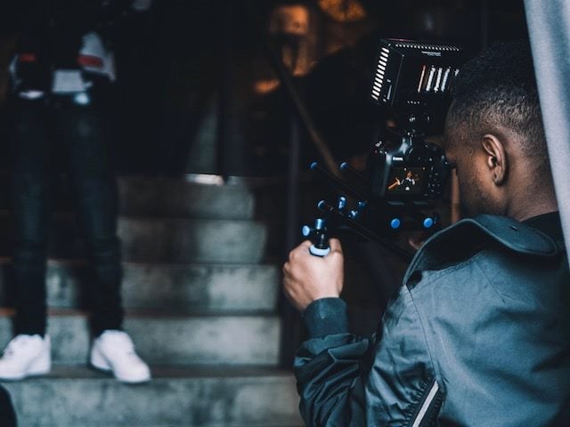 man filming another man who is standing on stairs