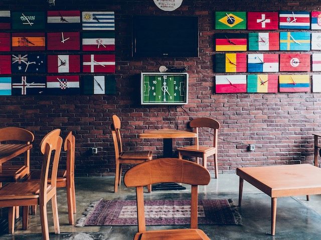 empty cafe with wall covered in clocks made from flags around the world