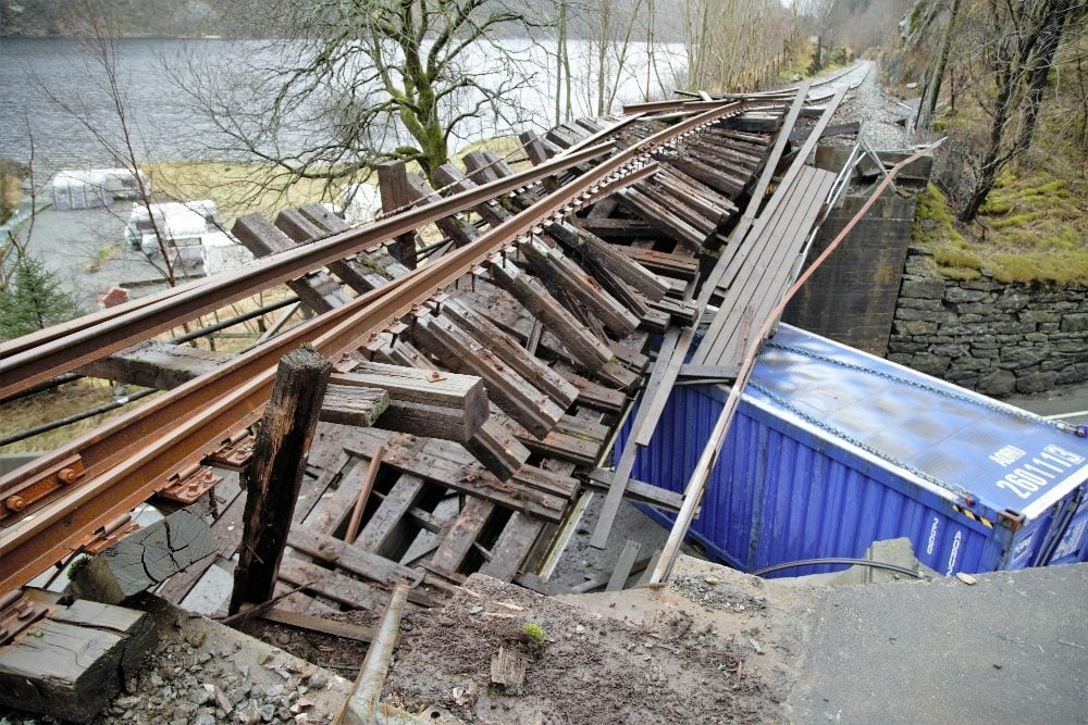 A broken railroad bridge with a blue truck trailer wedged underneath in piece about search engine decline.