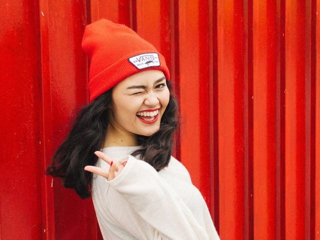winking woman standing in front of a red wall