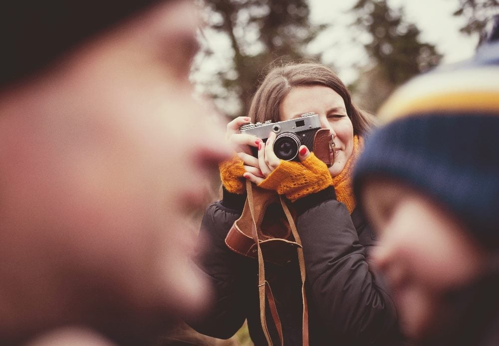 A woman shoots a picture of a man and child with a vintage camera in piece about customer loyalty strategies.