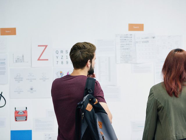 two people looking at a series of posters on a wall