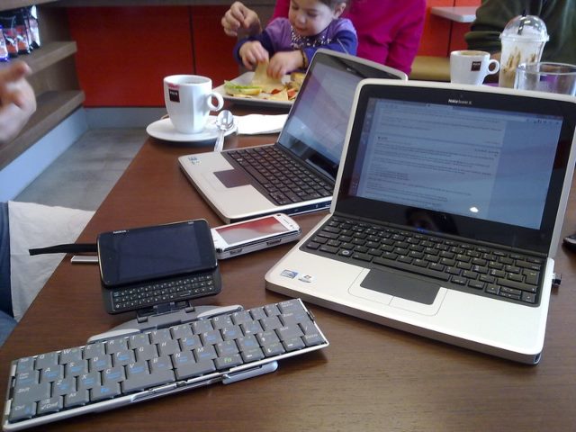A table with several laptops and phones on it.