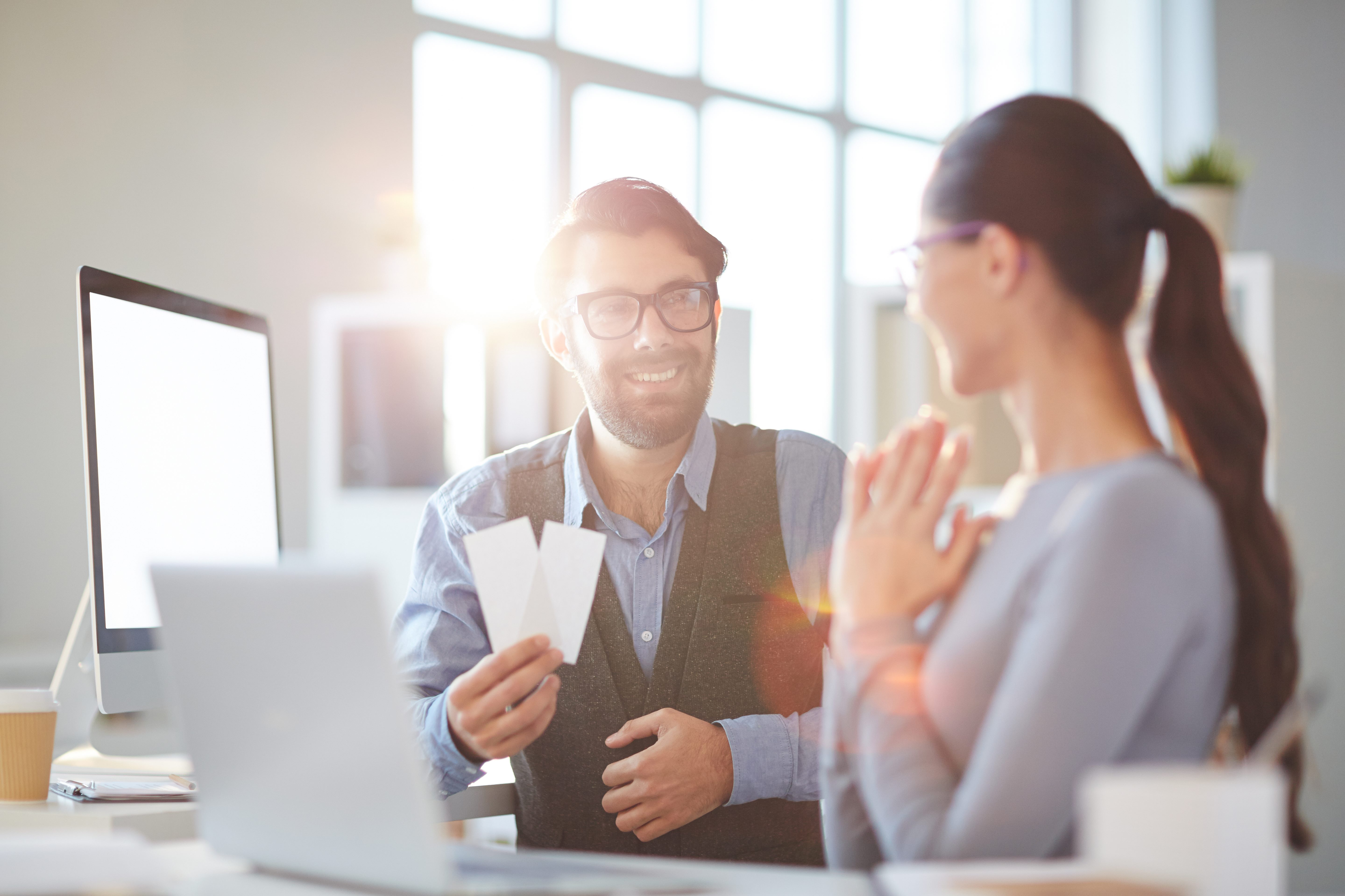 man presenting woman with tickets at work