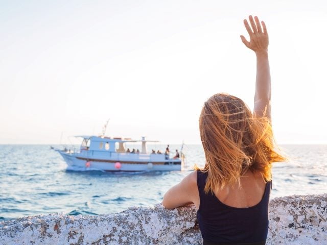 Young woman waving to a boat from the pier, just like we may wave goodbye to the term marketing technology in favor of customer technology.