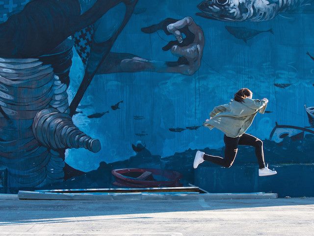 high leap in front of a mural