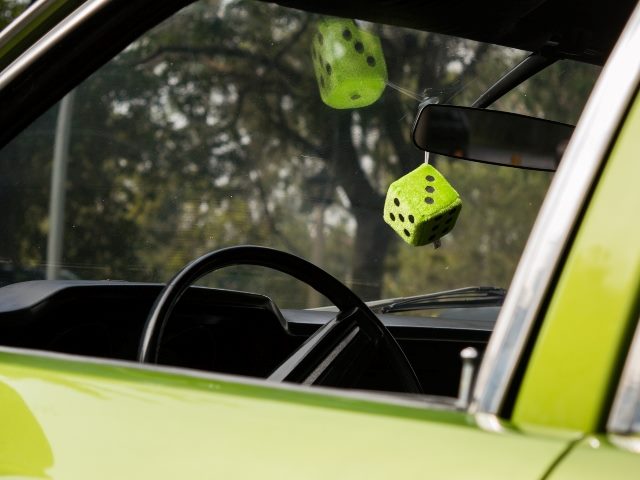 Dice hanging from rear-view mirror in car.