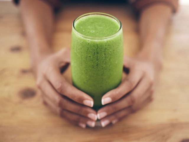 Hands, glass and detox, green-colored smoothie. 
