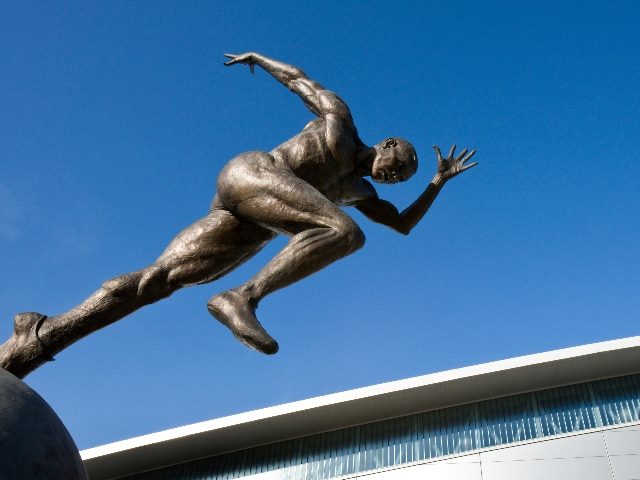 Statue of a man running against a background of a vibrant blue sky in piece about generative AI in technology.