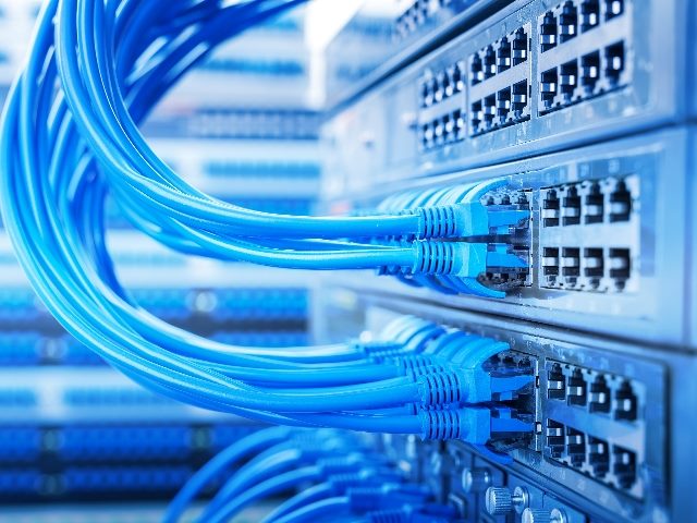 Bright-blue-colored network switch and ethernet cable in a Data Center in piece about data center pollution .