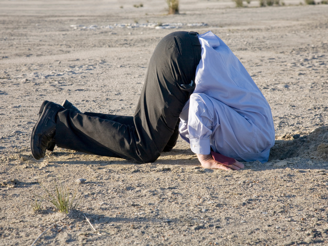 A businessman with his head in the sand