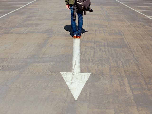 man standing with his back to an arrow