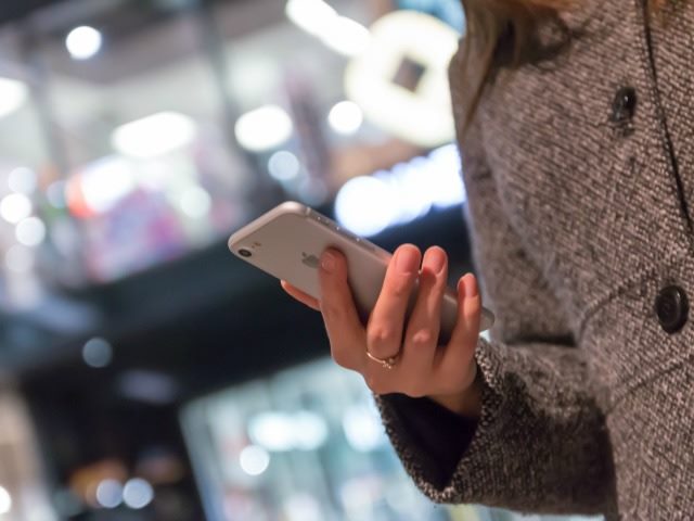 woman with cell phone by shopping area in winter