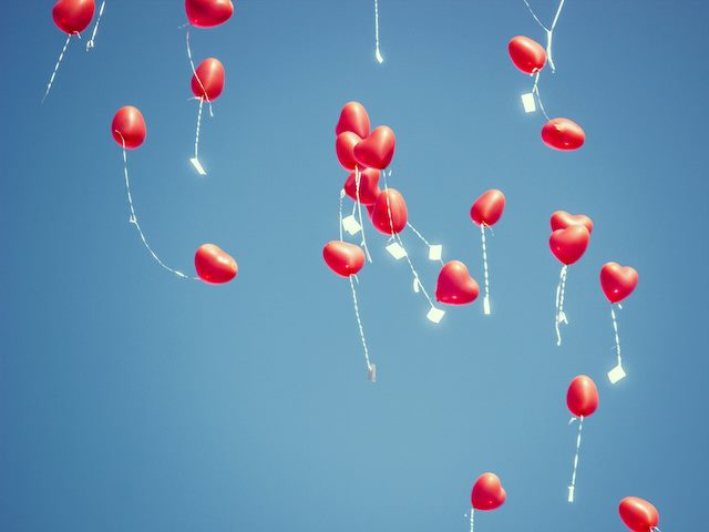 heart shaped balloons floating up in the sky
