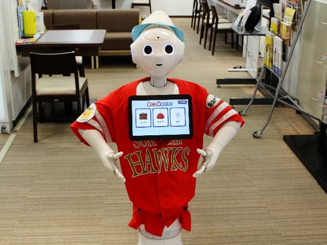 A Softbank Pepper robot on customer service at the front of a Softbank store in Makuhari, wearing a Softbank Hawks uniform, a baseball team sponsored by the company.