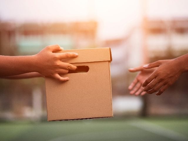 People, just showing their hands, exchanging a box. 