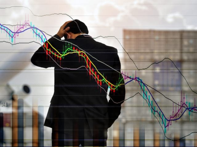 A sad businessman scratching his head with a declining sales data background