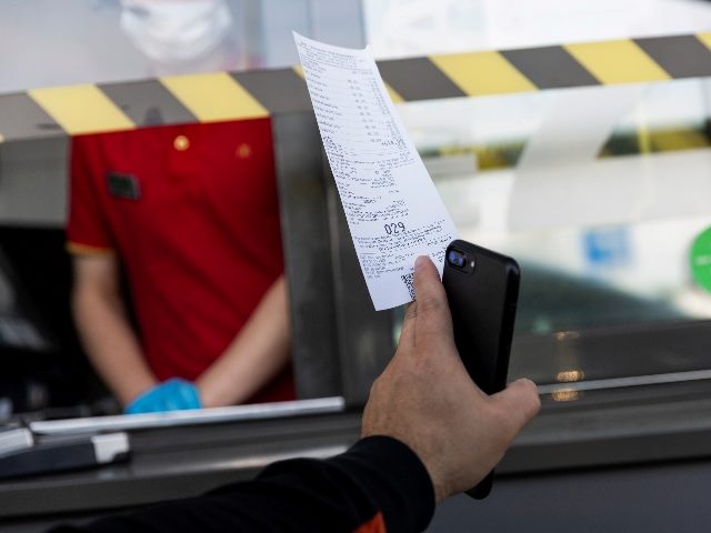 Driver in a car with a McDonald's receipt showing a worker his receipt in the drive-through, demonstrating the potential for great CX and EX.