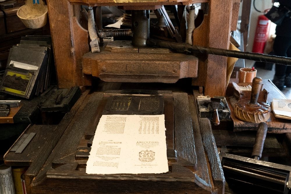 An antique wooden printing press that was operated by hand in piece about Elon Musk's plan to use Grok as a news summarizer on X.