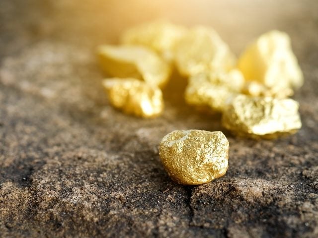 Pure gold pieces found in a mine on a stone floor.
